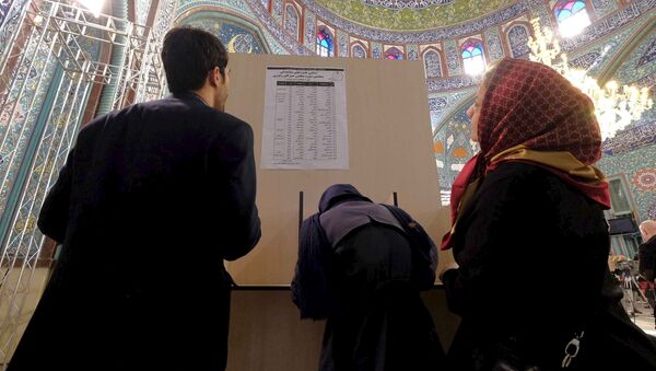 Iranians look at a list of candidates' names during elections for the parliament and Assembly of Experts, which has the power to appoint and dismiss the supreme leader, at a polling station in Tehran February 26, 2016 - Sputnik International