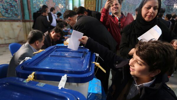 An Iranian boy casts his father ballot for both parliamentary elections and the Assembly of Experts at a polling station in Tehran on February 26, 2016 - Sputnik International