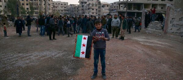 A boy carries an opposition flag as rebel fighters and civilians gather during the arrival of an aid convoy of Syrian Arab Red Crescent and United Nation (UN) to the rebel held besieged town of Kafr Batna, on the outskirts of Damascus, Syria February 23, 2016 A boy carries an opposition flag as rebel fighters and civilians gather during the arrival of an aid convoy of Syrian Arab Red Crescent and United Nation (UN) to the rebel held besieged town of Kafr Batna, on the outskirts of Damascus, Syria February 23, 2016 - Sputnik International