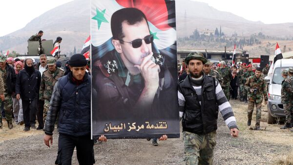 Syrian volunteers and their relatives wave the national flag and portraits of President Bashar al-Assad as they celebrate at the end of a paramilitary training conducted by the Syrian army in al-Qtaifeh, 50 kms north of the capital Damascus on February 22, 2016 - Sputnik International