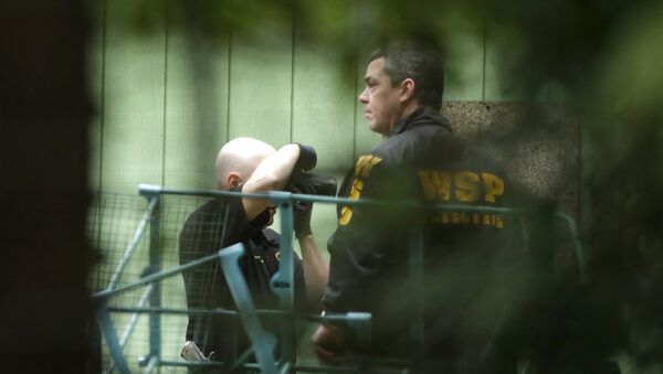 Investigators are seen through trees as they photographs the scene of a fatal shooting Friday, Feb. 26, 2016, near Belfair, Wash - Sputnik International