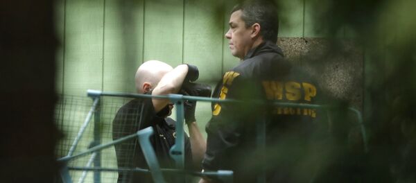 Investigators are seen through trees as they photographs the scene of a fatal shooting Friday, Feb. 26, 2016, near Belfair, Wash - Sputnik International