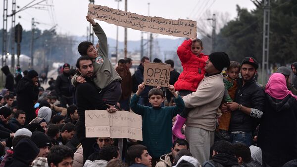 Syrian and Iraqi refugees trapped at the Greek-Macedonian borders demonstrate shouting 'open the border' as they block the train tracks on February 28, 2016 - Sputnik International