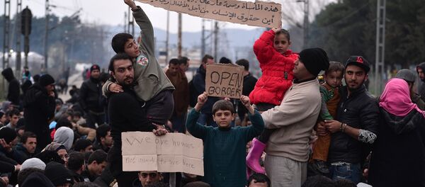 Syrian and Iraqi refugees trapped at the Greek-Macedonian borders demonstrate shouting 'open the border' as they block the train tracks on February 28, 2016 - Sputnik International