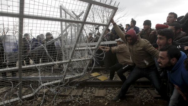 Stranded refugees and migrants try to bring down part of the border fence during a protest at the Greek-Macedonian border, near the Greek village of Idomeni, February 29, 2016 - Sputnik International