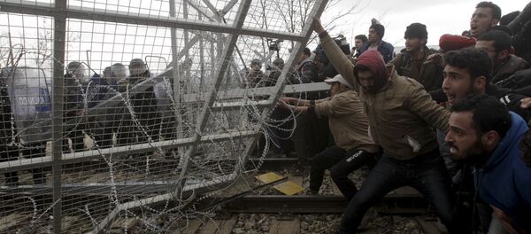 Stranded refugees and migrants try to bring down part of the border fence during a protest at the Greek-Macedonian border, near the Greek village of Idomeni, February 29, 2016 - Sputnik International