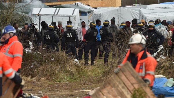 Agents dismantle a shelter as anti-riot policemen stand nearby on February 29, 2016 in the jungle migrants and refugees camp in Calais, northern France - Sputnik International