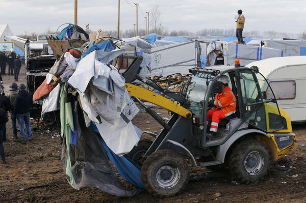 A bulldozer clears away debris from makeshift shelters. A bulldozer clears away debris from makeshift shelters. - Sputnik International
