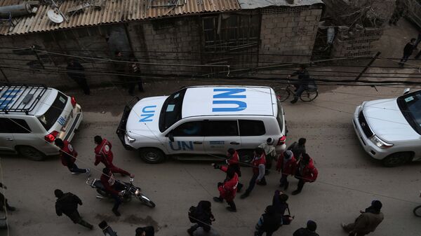 UN vehicles escorting a Red Crescent convoy carrying humanitarian aid arrive in Kafr Batna, in the rebel-held Eastern Ghouta area, on the outskirts of the capital Damascus on February 23, 2016 during an operation in cooperation with the UN to deliver aid to thousands of besieged Syrians. - Sputnik International