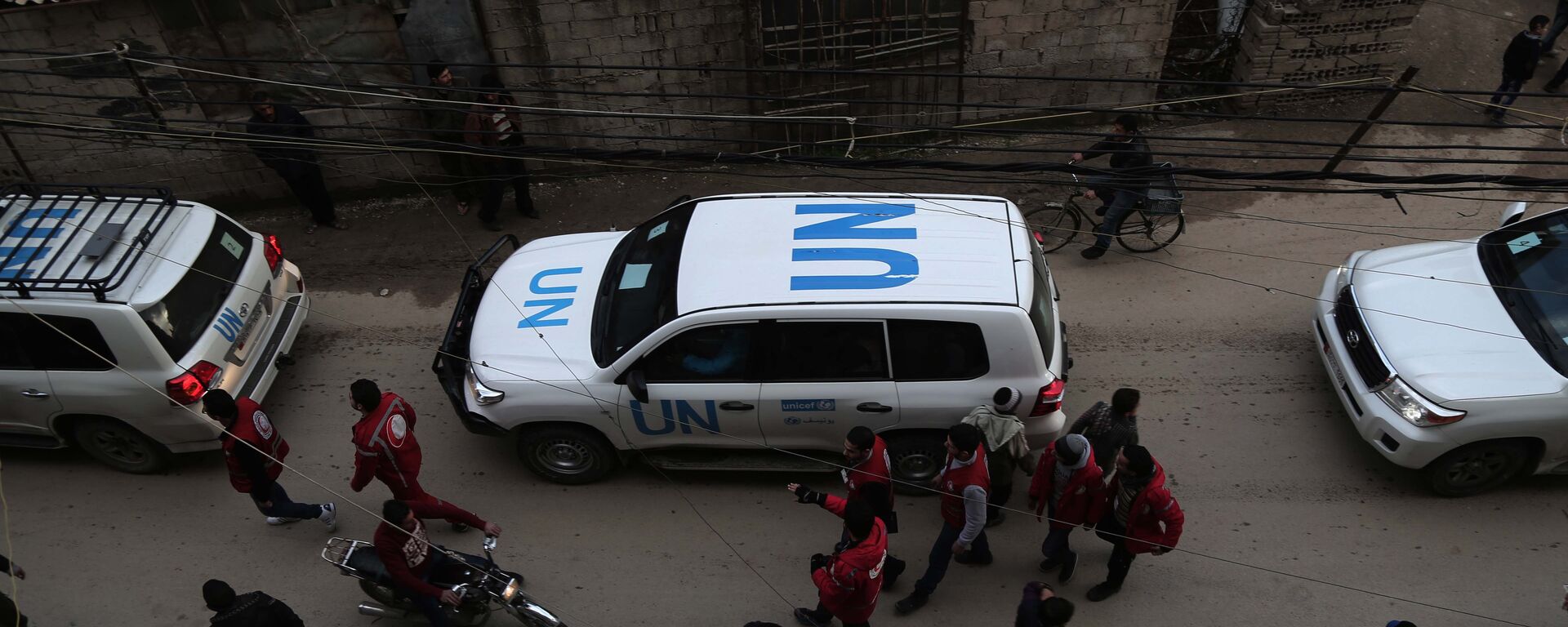 UN vehicles escorting a Red Crescent convoy carrying humanitarian aid arrive in Kafr Batna, in the rebel-held Eastern Ghouta area, on the outskirts of the capital Damascus on February 23, 2016 during an operation in cooperation with the UN to deliver aid to thousands of besieged Syrians. - Sputnik International, 1920, 12.07.2022
