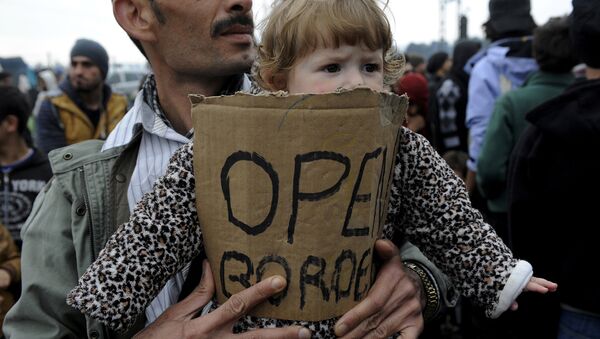 A stranded refugee holds a child during a protest at the Greek-Macedonian border as they wait for the border crossing to reopen near the Greek village of Idomeni, February 28, 2016. - Sputnik International