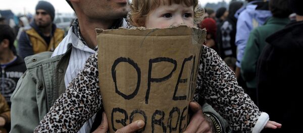 A stranded refugee holds a child during a protest at the Greek-Macedonian border as they wait for the border crossing to reopen near the Greek village of Idomeni, February 28, 2016. - Sputnik International