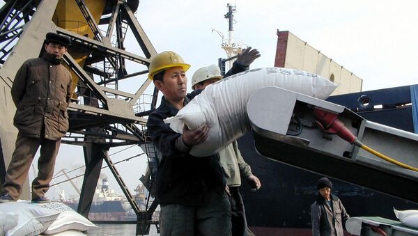 North Korean dock workers unload sacks of donated wheat onto a truck at Nampo port. (File) - Sputnik International