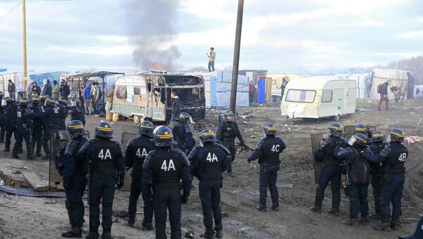 French CRS riot police group near burning makeshift shelters during a protest by migrants against the partial dismantlement of the camp for migrants called the jungle, in Calais, northern France, February 29, 2016. - Sputnik International