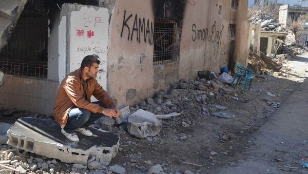 A resident of Cizre sits next to his ruined and burned house. - Sputnik International