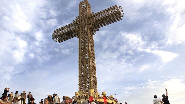 Macedonian Orthodox believers sit around a massive metal cross during its sanctification ceremony on top of Mt. Vodno, just above Macedonia's capital Skopje, on Wednesday, Aug. 28, 2002 - Sputnik International