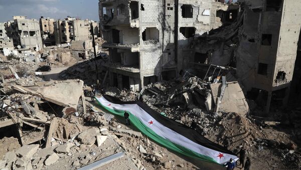 Residents and activists hold a giant a pre-Baath Syrian flag, now used by the Syrian opposition, during an anti-regime protest in the rubble of destroyed buildings in the neighbourhood of Jobar, on the eastern outskirts of the capital Damascus, on March 3, 2016 - Sputnik International