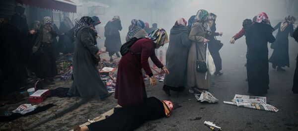 Women helps another woman who felt as Turkish anti-riot police officers launch tear gas to disperse supporters in front of the headquarters of the Turkish daily newspaper Zaman in Istanbul on March 5, 2016, after Turkish authorities seized the headquarters in a midnight raid - Sputnik International