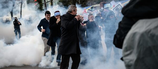 Men run and cover their faces as Turkish anti-riot police officers use tear gas to disperse supporters in front of the headquarters of the Turkish daily newspaper Zaman in Istanbul on March 5, 2016, after Turkish authorities seized the headquarters in a midnight raid Men run and cover their faces as Turkish anti-riot police officers use tear gas to disperse supporters in front of the headquarters of the Turkish daily newspaper Zaman in Istanbul on March 5, 2016, after Turkish authorities seized the headquarters in a midnight raid - Sputnik International