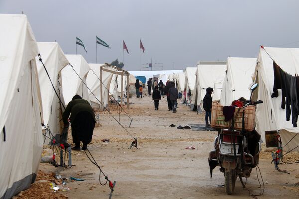 Displaced Syrians fleeing areas in the northern embattled province of Aleppo, walk past tents at the Bab al-Salama camp, set up outside the Syrian city of Azaz on Syria's northern border with Turkey on February 12, 2016 Displaced Syrians fleeing areas in the northern embattled province of Aleppo, walk past tents at the Bab al-Salama camp, set up outside the Syrian city of Azaz on Syria's northern border with Turkey on February 12, 2016 - Sputnik International