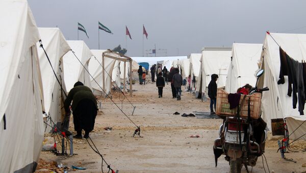 Displaced Syrians fleeing areas in the northern embattled province of Aleppo, walk past tents at the Bab al-Salama camp, set up outside the Syrian city of Azaz on Syria's northern border with Turkey on February 12, 2016 - Sputnik International