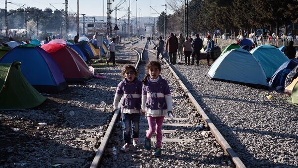 Sisters walk on railway tracks where refugees installed their tents at the makeshift camp of the Greek-Macedonian border near the Greek village of Idomeni, on March 5, 2016, where thousands of refugees and migrants wait to cross the border into Macedonia - Sputnik International