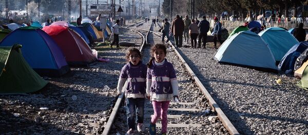 Sisters walk on railway tracks where refugees installed their tents at the makeshift camp of the Greek-Macedonian border near the Greek village of Idomeni, on March 5, 2016, where thousands of refugees and migrants wait to cross the border into Macedonia - Sputnik International
