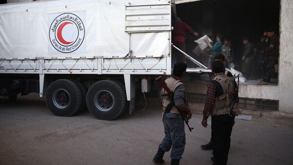 Syrian rebel fighters stand guard as sacs of aid are unloaded from a Syrian Arab Red Crescent truck in Hammuriya, in the eastern Ghouta region, a rebel stronghold east of the Syrian capital Damascus during a UN-led operation to deliver food and medical supplies - Sputnik International
