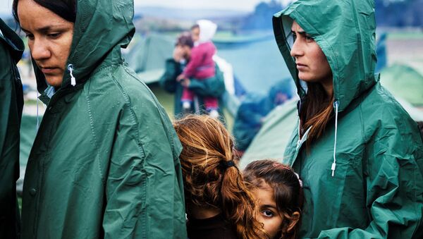 Migrants queue for a food distribution under the rain on March 10, 2016, in a makeshift camp at the Greek-Macedonian border, near the Greek village of Idomeni. - Sputnik International