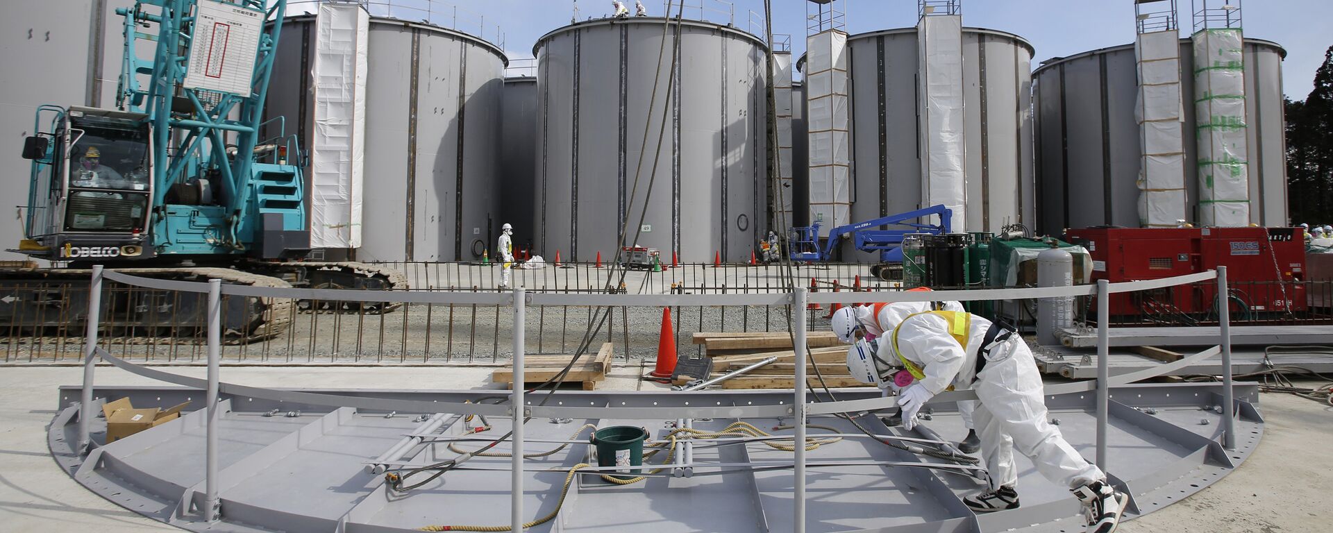 Men wearing protective suits and masks work in front of welding storage tanks for radioactive water, under construction in the J1 area at the Tokyo Electric Power Co's (TEPCO) tsunami-crippled Fukushima Daiichi nuclear power plant in Okuma in Fukushima prefecture. (File) - Sputnik International, 1920, 13.04.2021