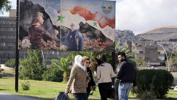 Syrians walk past a billboard bearing a national flag and a slogan which reads in Arabic You are the future and long live the country in Damascus on December 2, 2015 - Sputnik International