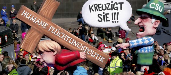 A carnival float with papier-mache caricature mocking German Chancellor Angela Merkel is displayed at a postponed Rosenmontag (Rose Monday) parade, at one location in Duesseldorf, Germany, March 13, 2016. Words read 'Crucify her' 'Humane politics for migrants' A carnival float with papier-mache caricature mocking German Chancellor Angela Merkel is displayed at a postponed Rosenmontag (Rose Monday) parade, at one location in Duesseldorf, Germany, March 13, 2016. Words read 'Crucify her' 'Humane politics for migrants' - Sputnik International
