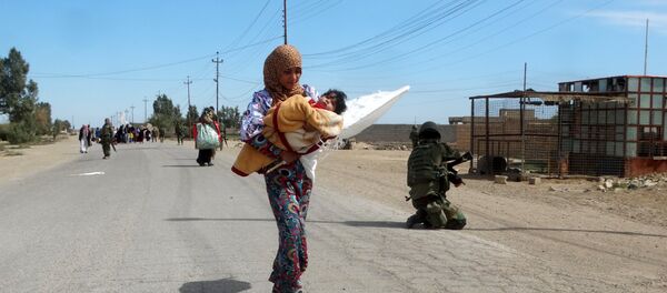 A woman carrying her child flees to safe areas with help from Iraqi security forces, west of Ramadi, March 9, 2016 A woman carrying her child flees to safe areas with help from Iraqi security forces, west of Ramadi, March 9, 2016 - Sputnik International