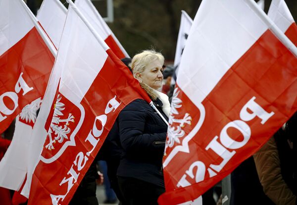 A woman holds the Polish national flag as she takes part in a march demanding their government to respect the country's constitution in Warsaw, Poland, March 12, 2016.  - Sputnik International