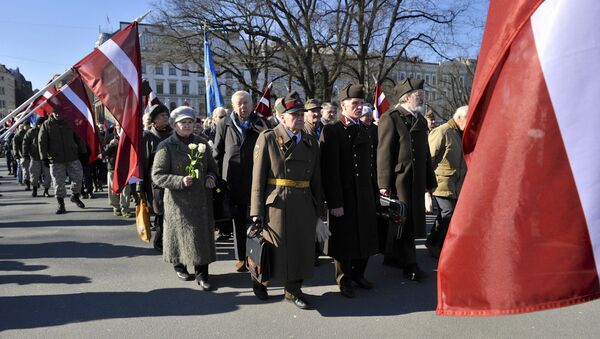 People carry flowers and Latvian flags as they march to the Freedom Monument to commemorate World War II veterans who fought in Waffen SS divisions, in Riga, Latvia, Monday, March 16, 2015 - Sputnik International