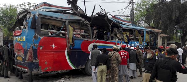Policemen and rescue officials walk near a bus damaged in a bomb blast in Peshawar, Pakistan March 16, 2016 - Sputnik International
