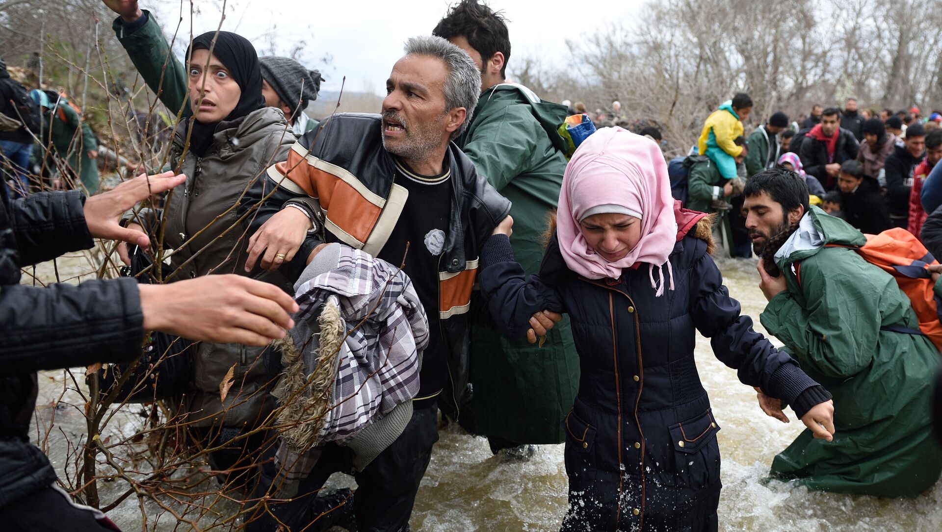 Беженцы и мигранты пересекают реку по пути в Македонию из импровизированного лагеря на греко-македонской границе - Sputnik International, 1920, 12.07.2021