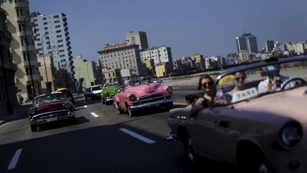 Tourists ride in a vintage car at the 'Malecon' seafront in Havana, March 16, 2016. - Sputnik International