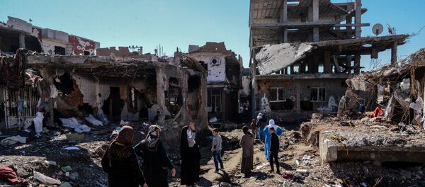 Woman walk next to ruined houses and shops on March 8, 2016 during International Women's day in Cizre district. Residents of Cizre in southeastern Turkey began returning home Wednesday after authorities partially lifted a curfew in place since December for a controversial operation against Kurdish rebels which left many homes destroyed. - Sputnik International