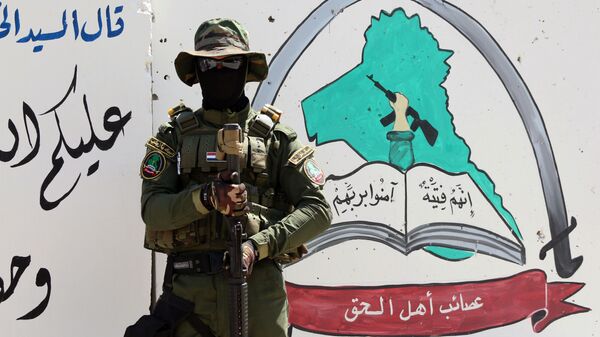 An Iraqi fighter of the Shiite group Asaib Ahl al-Haq (The League of the Righteous) stands guard outside the militia's headquarters on May 18, 2015 in the Iraqi mainly Shiite southern city of Basra - Sputnik International