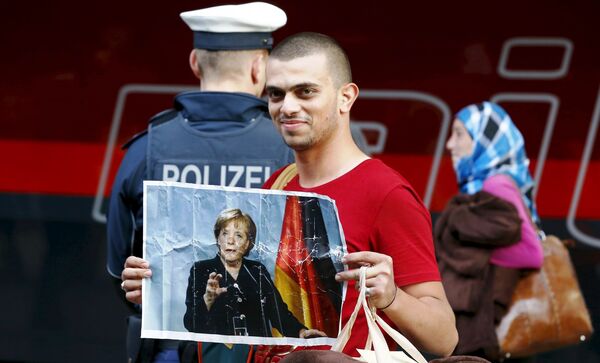 A migrant holds a picture of German Chancellor Angela Merkel after arriving to the main railway station in Munich, Germany, in this September 5, 2015. A migrant holds a picture of German Chancellor Angela Merkel after arriving to the main railway station in Munich, Germany, in this September 5, 2015. - Sputnik International