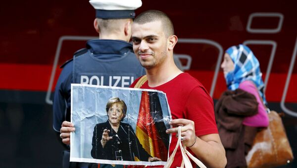 A migrant holds a picture of German Chancellor Angela Merkel after arriving to the main railway station in Munich, Germany, in this September 5, 2015. - Sputnik International