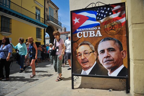 Tourists walk next to a poster of Cuban President Raul Castro and US president Barack Obama in Havana, on March 18, 2016 - Sputnik International
