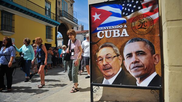 Tourists walk next to a poster of Cuban President Raul Castro and US president Barack Obama in Havana, on March 18, 2016 - Sputnik International