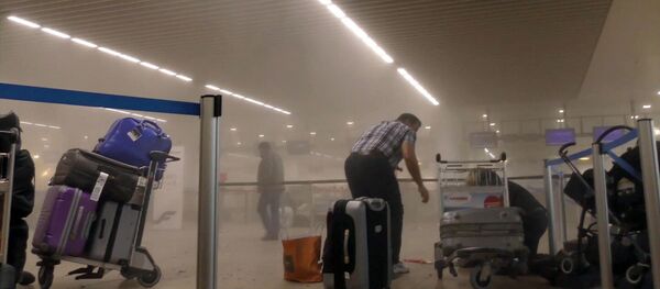 In this photo provided by Ralph Usbeck an unidentified traveller gets to his feet in a smoke filled terminal at Brussels Airport, in Brussels after explosions Tuesday, March 22, 2016 - Sputnik International