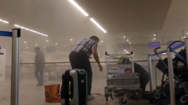 In this photo provided by Ralph Usbeck an unidentified traveller gets to his feet in a smoke filled terminal at Brussels Airport, in Brussels after explosions Tuesday, March 22, 2016 - Sputnik International