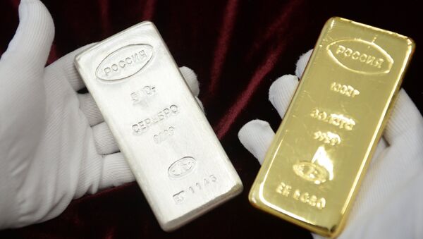 A worker holds a gold bar and a silver bar produced during the opening of a new bank bar manufacturing line at the Yekaterinburg Plant for Non-Ferrous Metals Processing, in the town of Verkhnyaya Pyshma, Sverdlovsk region. - Sputnik International