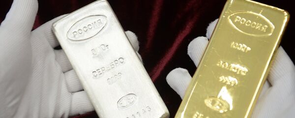 A worker holds a gold bar and a silver bar produced during the opening of a new bank bar manufacturing line at the Yekaterinburg Plant for Non-Ferrous Metals Processing, in the town of Verkhnyaya Pyshma, Sverdlovsk region. - Sputnik International