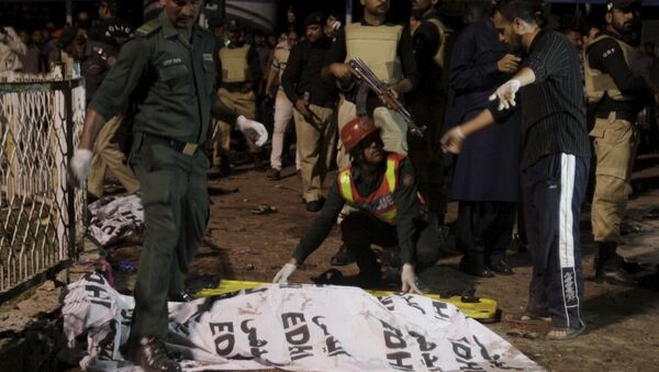 Rescue workers move a body from the site of a blast outside a public park in Lahore, Pakistan - Sputnik International