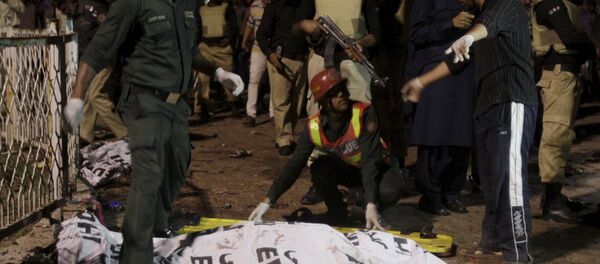 Rescue workers move a body from the site of a blast outside a public park in Lahore, Pakistan - Sputnik International